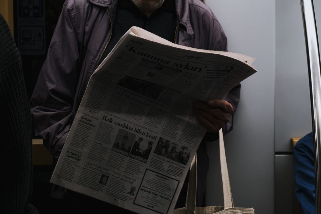 A man reads a newspaper in a dimly lit public transport setting, reflecting city life. — Avast Main Reliability Options