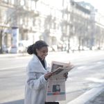 African American woman reading a newspaper on an urban street, enjoying a peaceful morning. — Cuando Ella Desea Ser Simplemen