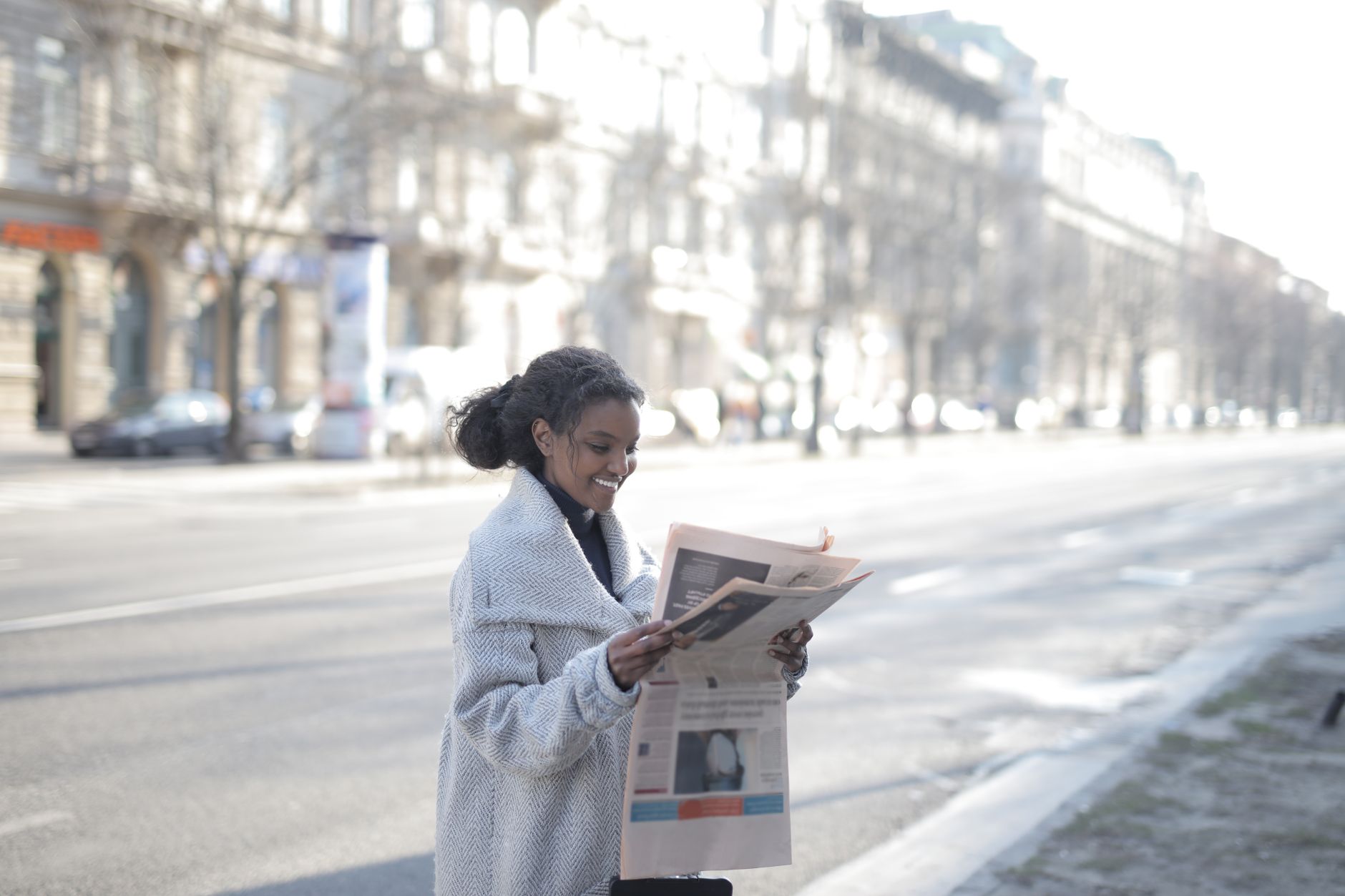 African American woman reading a newspaper on an urban street, enjoying a peaceful morning. — Cuando Ella Desea Ser Simplemen