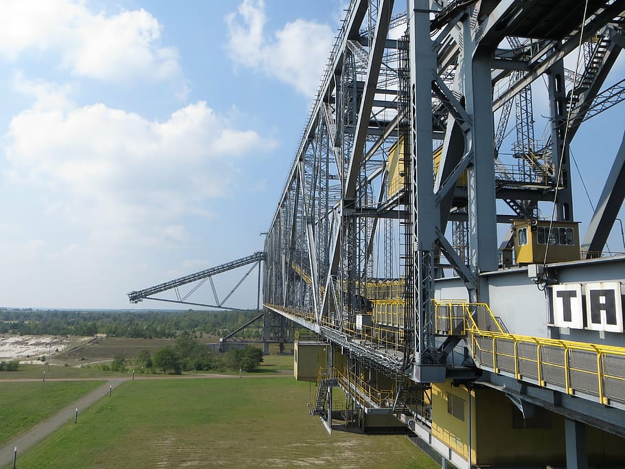 A large industrial construction machine against a blue sky and green landscape